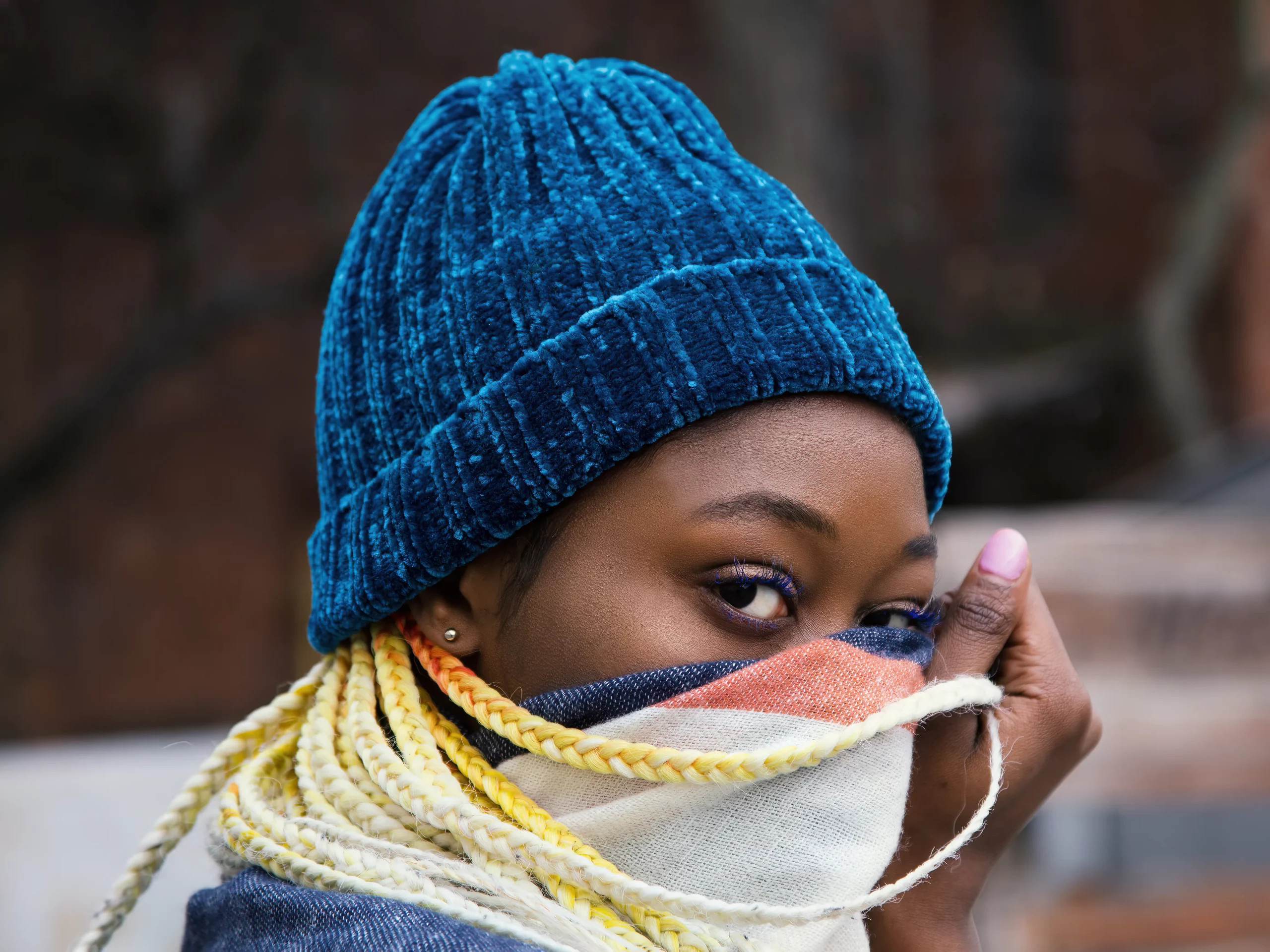 Black woman cover her face wearing blue beanie