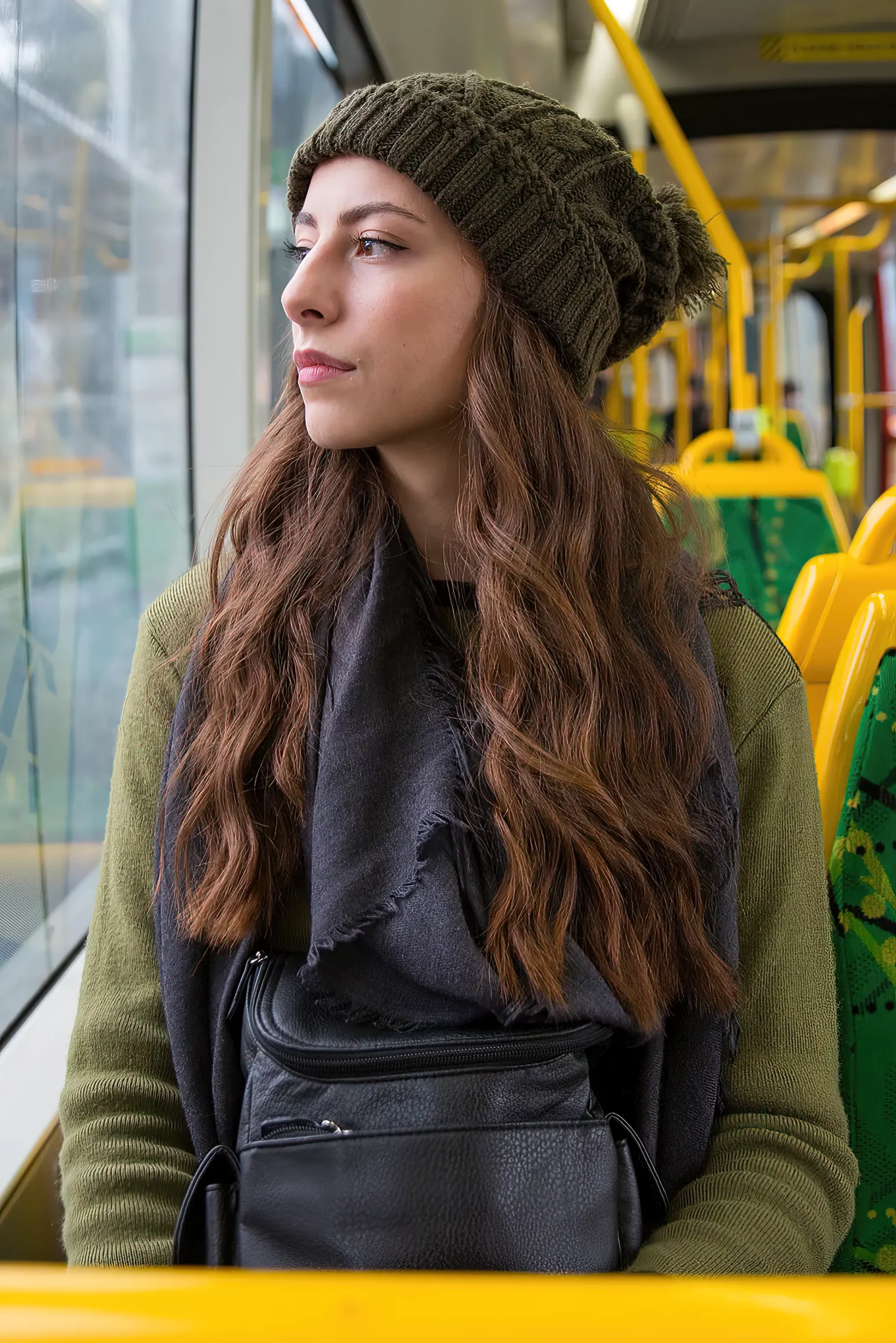 Young woman sitting alone on melbourne tram wearing a green beanie