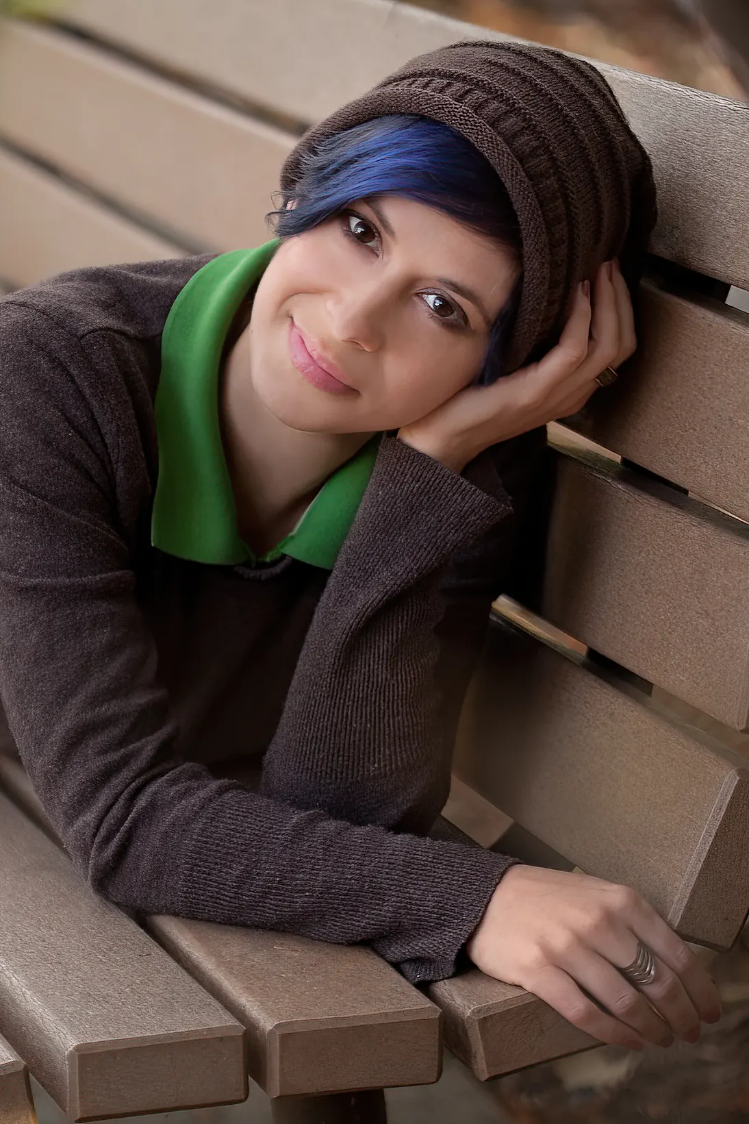 Smiling woman lying on park bench wearing a brown beanie