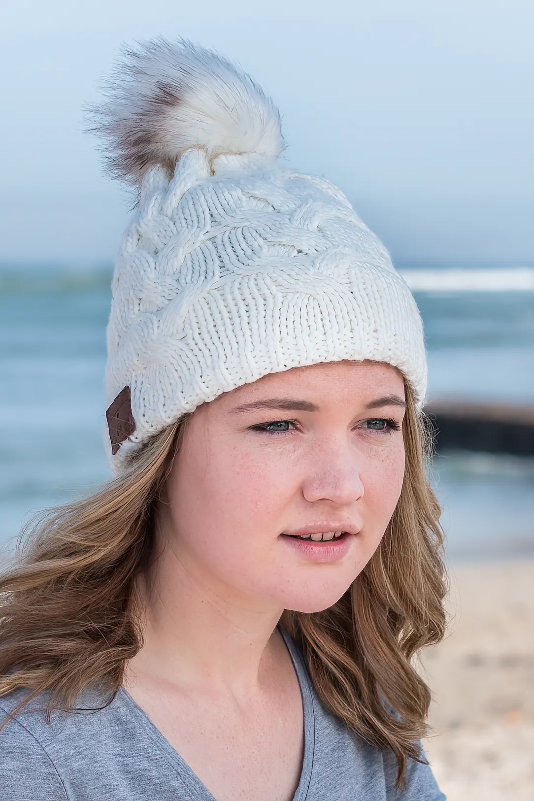 Female model wearing white knitted beanie with Bluetooth speakers inside