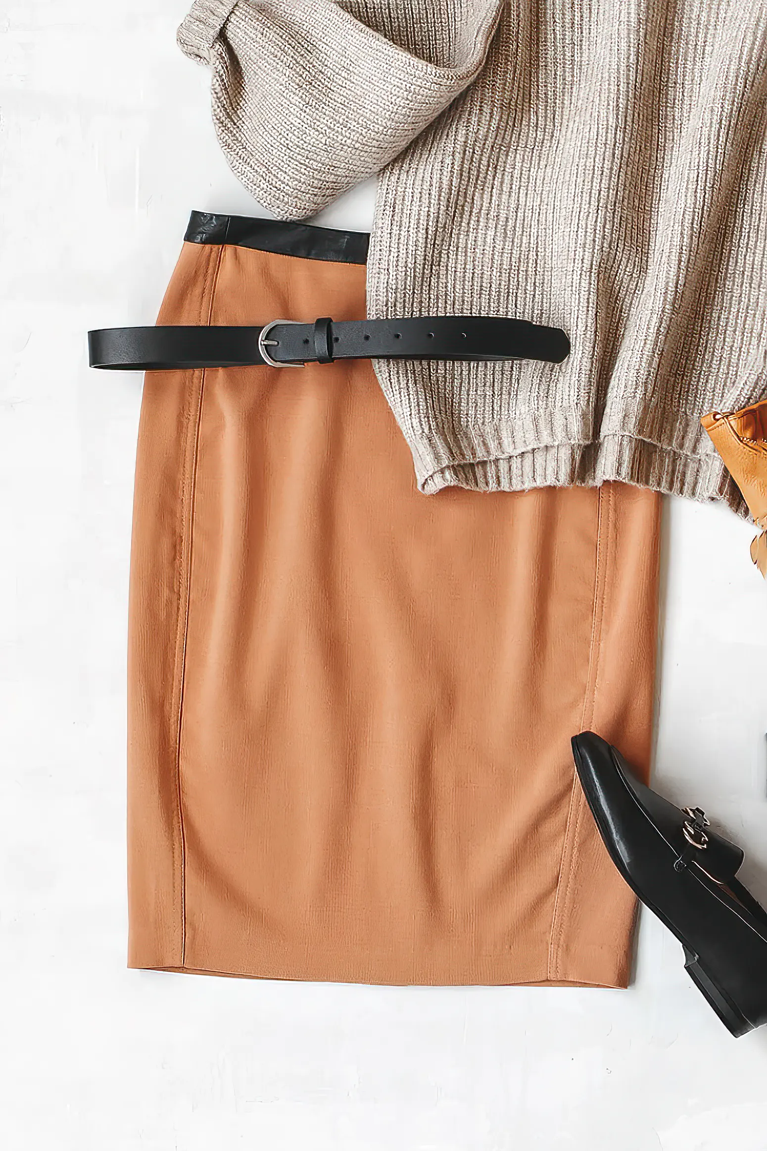 Brown midi pencil skirt, beige knitted oversize sweater, bag, belt, black loafers or flat shoes on grey background